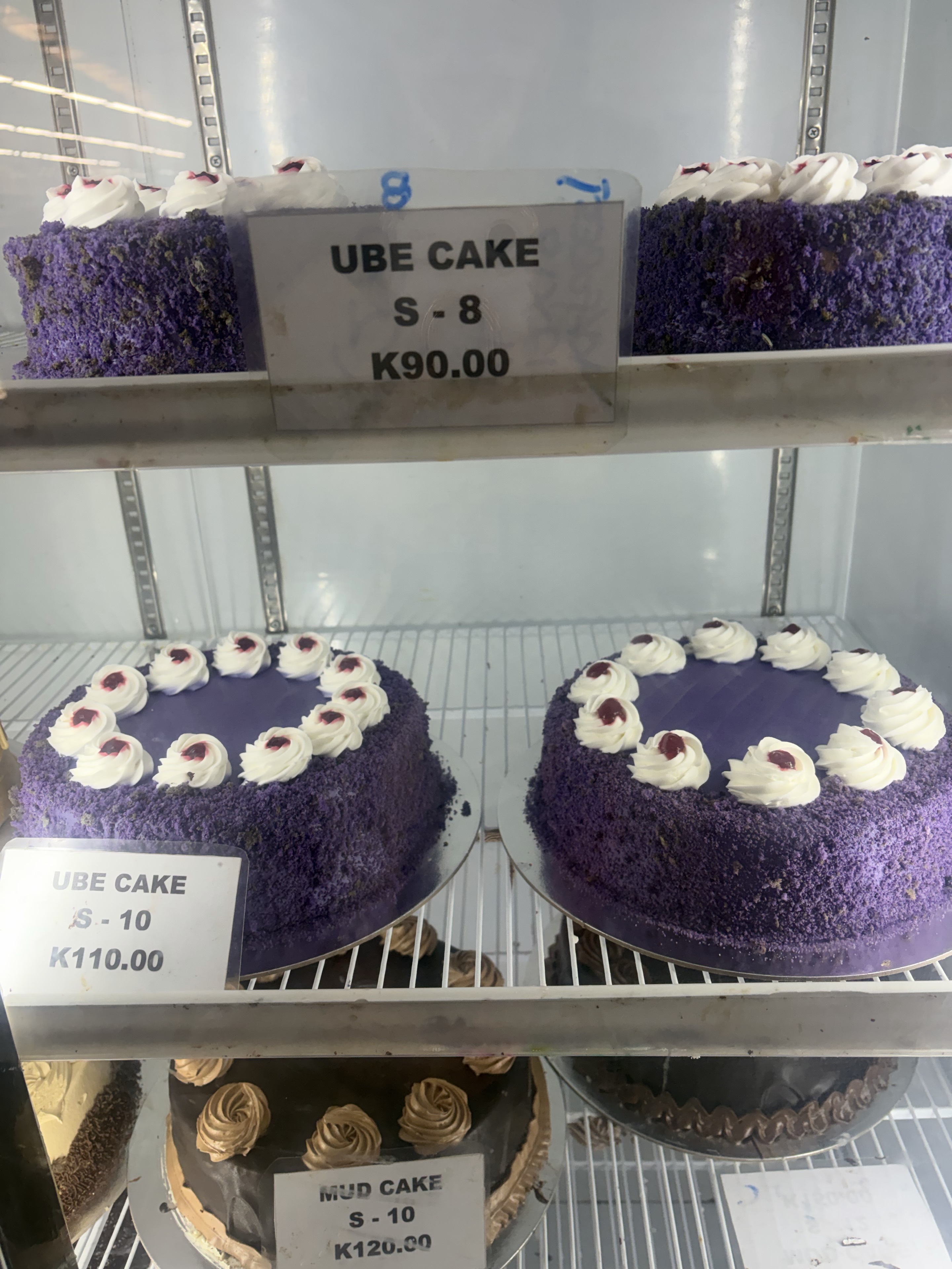 スーパーのショーケースに並ぶ紫色のウベケーキとマッドケーキ