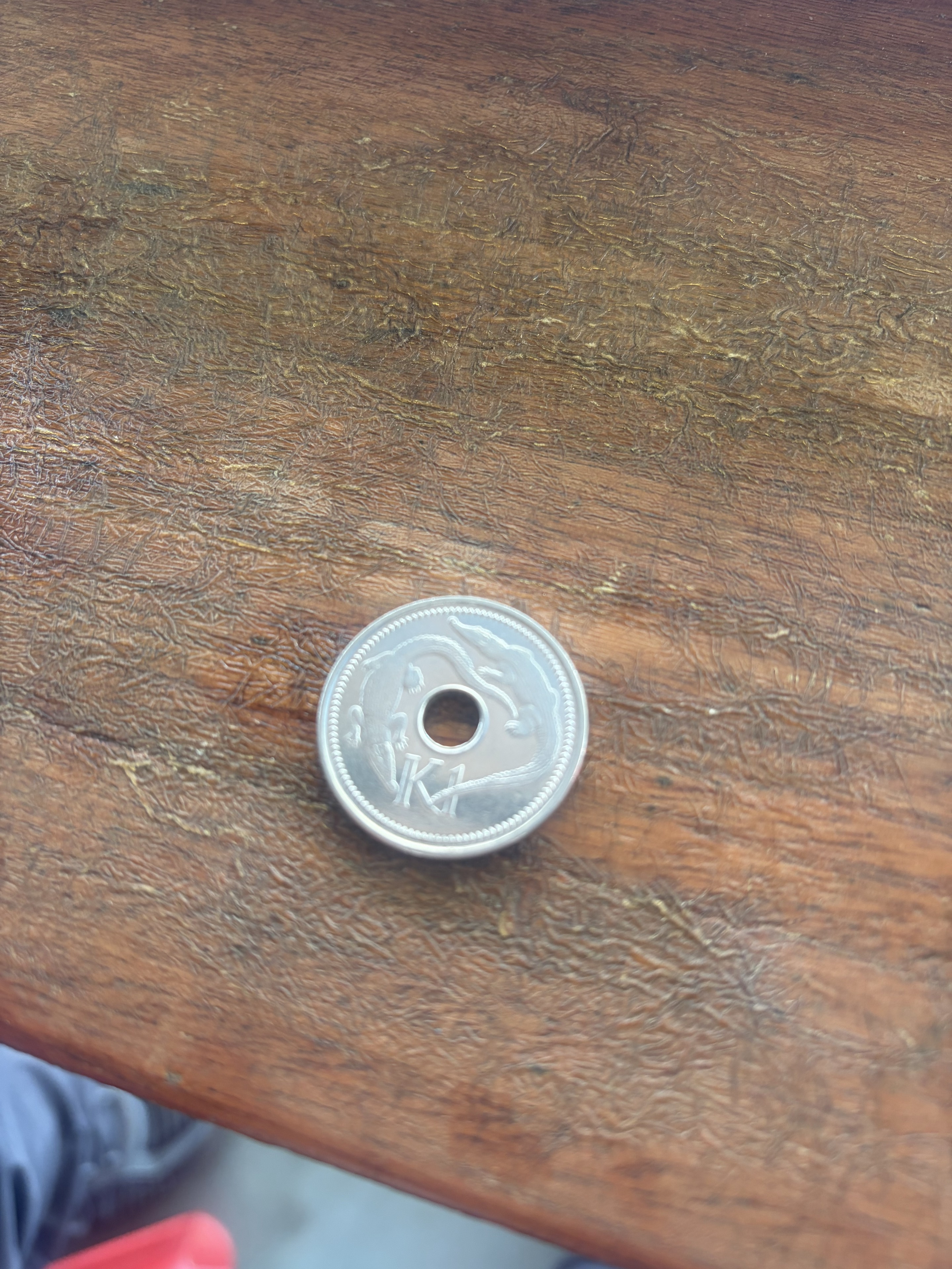 木のテーブルに置いたPNGの1キナ硬貨
